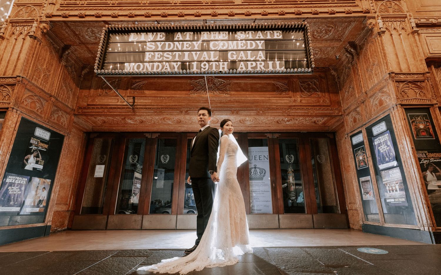Elegant wedding couple posing outside historic State Theatre Sydney at night.