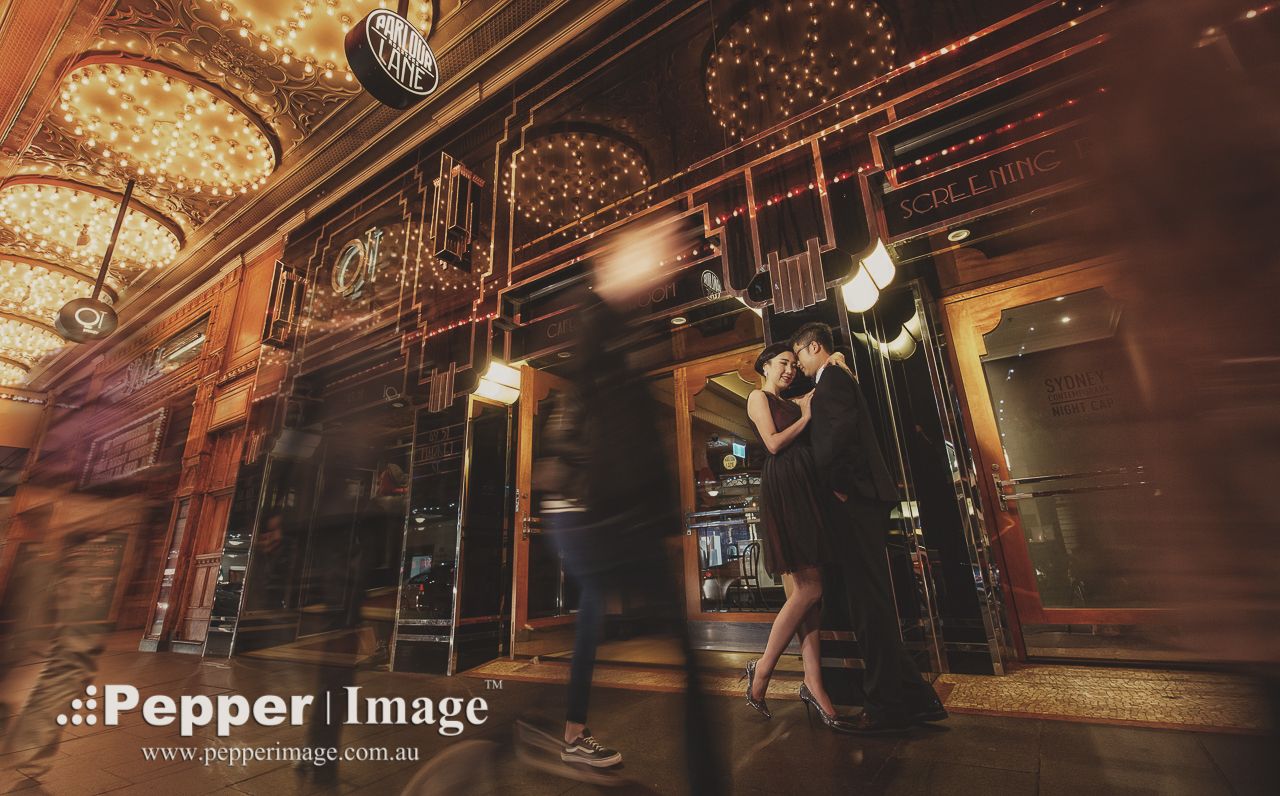 Couple embraces in a warmly lit ornate venue, captured in a dreamy motion-blur wedding portrait.
