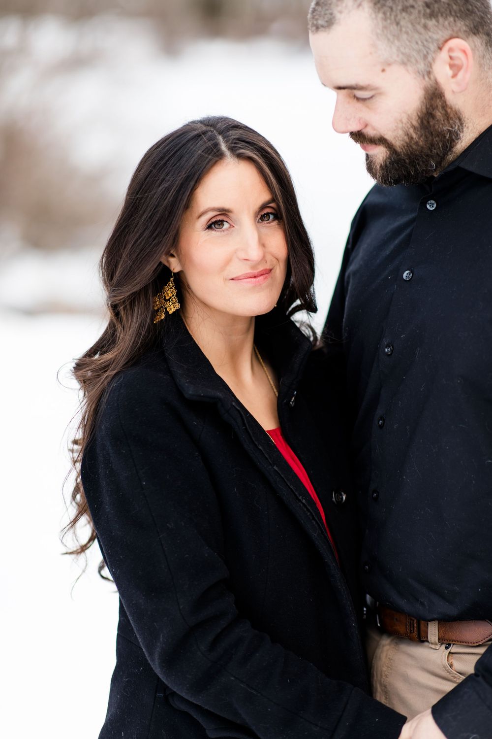 A winter couple's portrait featuring formal attire against a snowy backdrop.