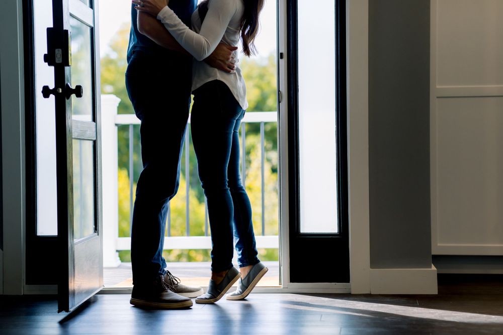 Silhouette of a couple embracing in a doorway with natural light streaming in.