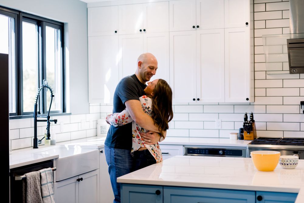 A romantic moment shared in a bright modern kitchen with white cabinets and subway tile backsplash.