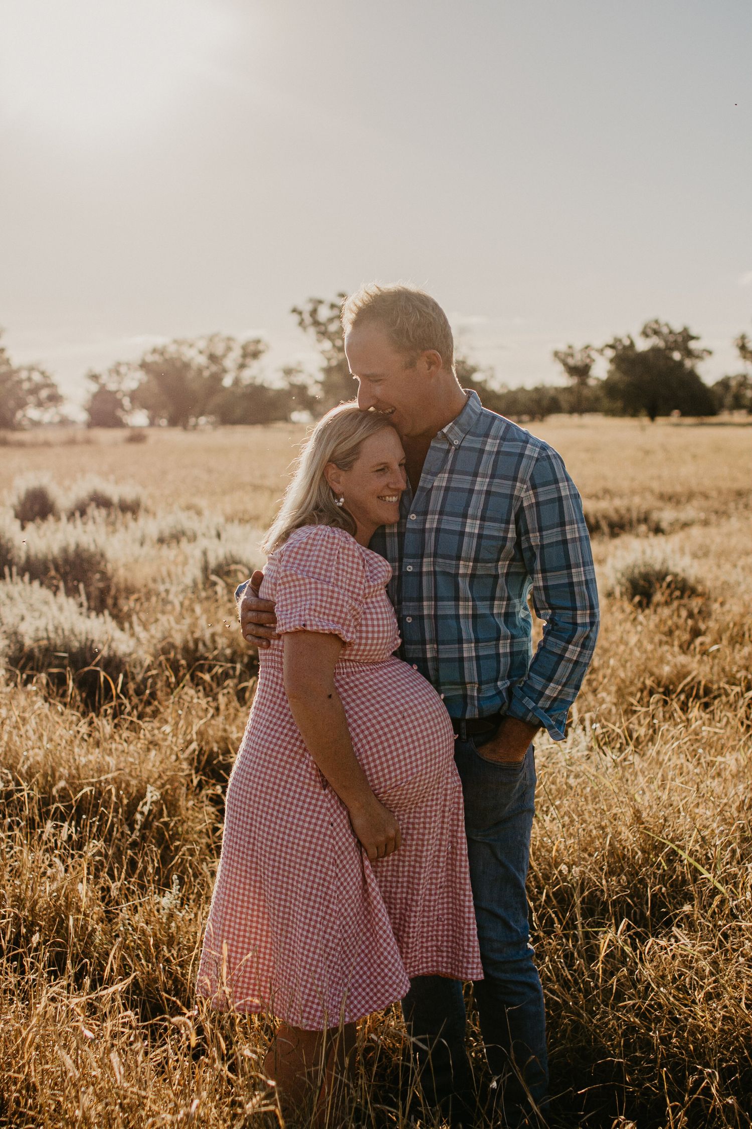 Pregnant wife & husband close together in a paddock
