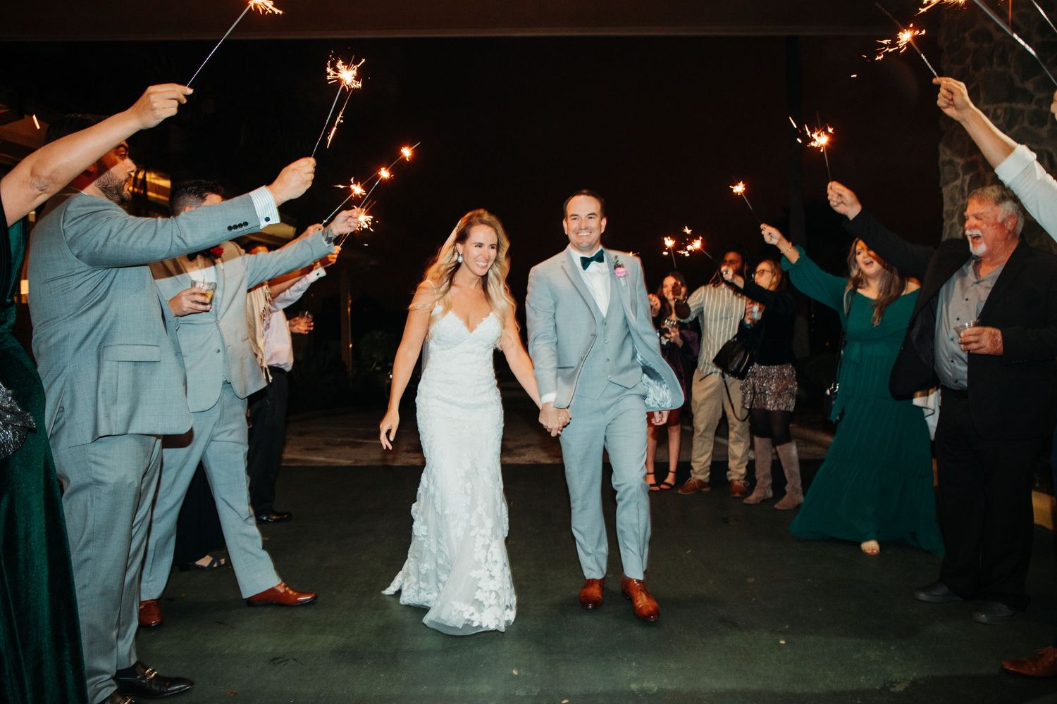 Newlyweds walking through sparkler exit with celebrating guests.