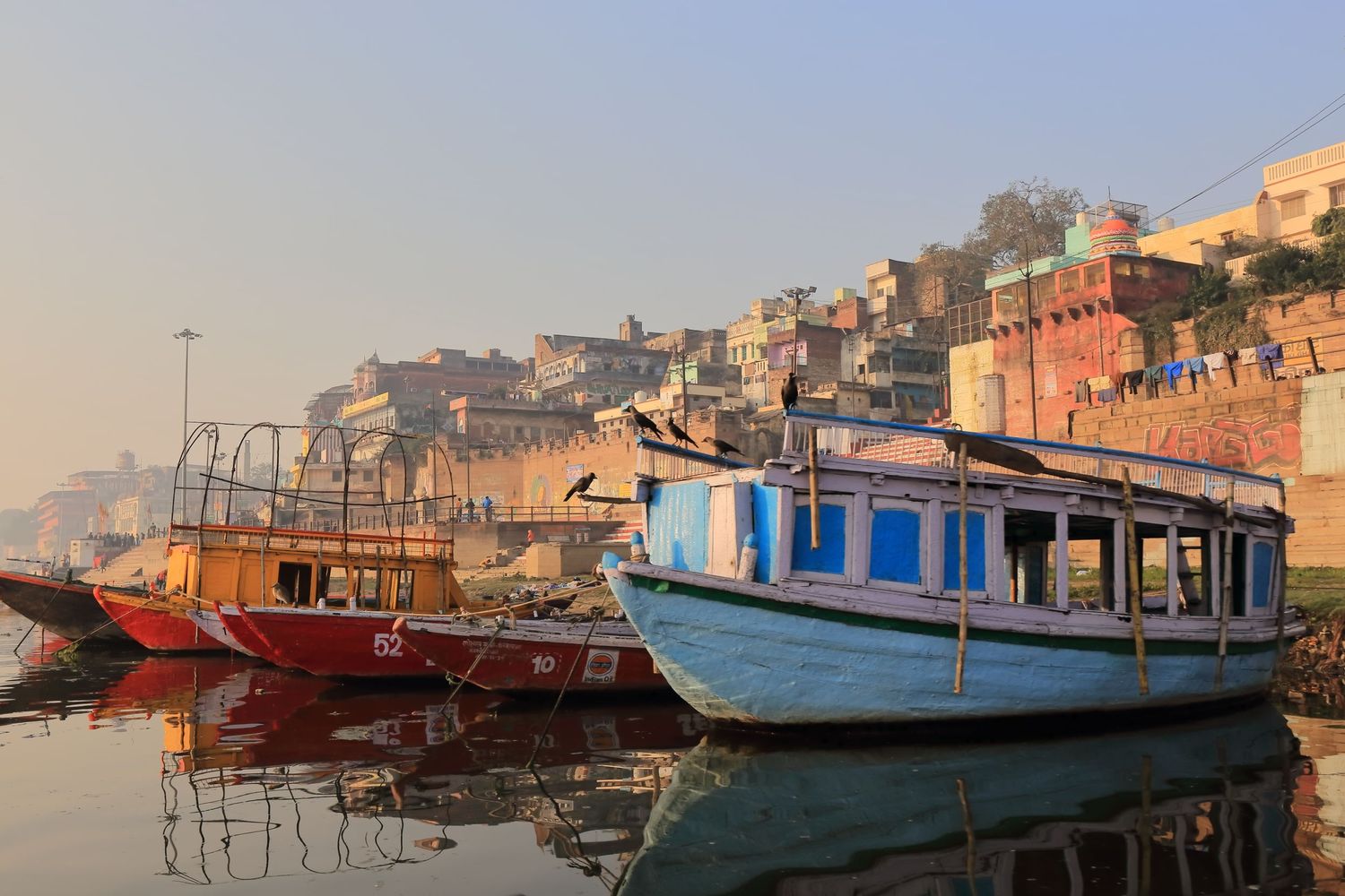 Colorful wooden boats moored along the misty riverbank of Varanasi.