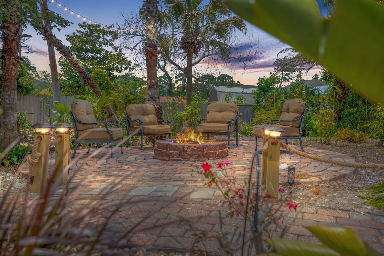 Stone patio seating area with loungers surrounded by tropical landscaping and palm trees.