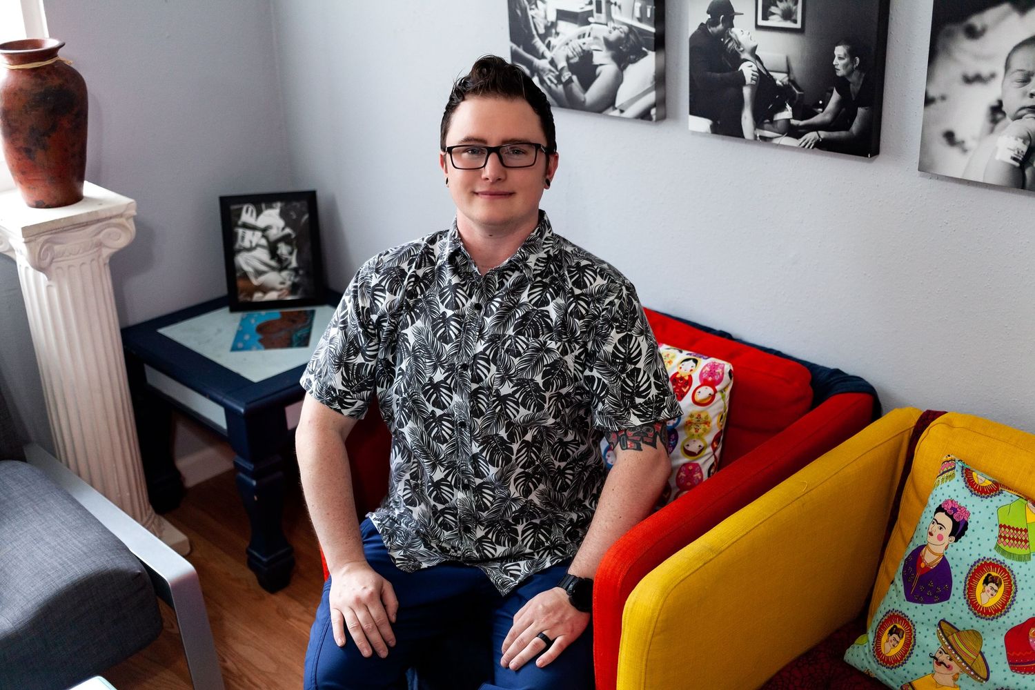A person wearing a black and white printed shirt sits on an orange chair next to a yellow chair