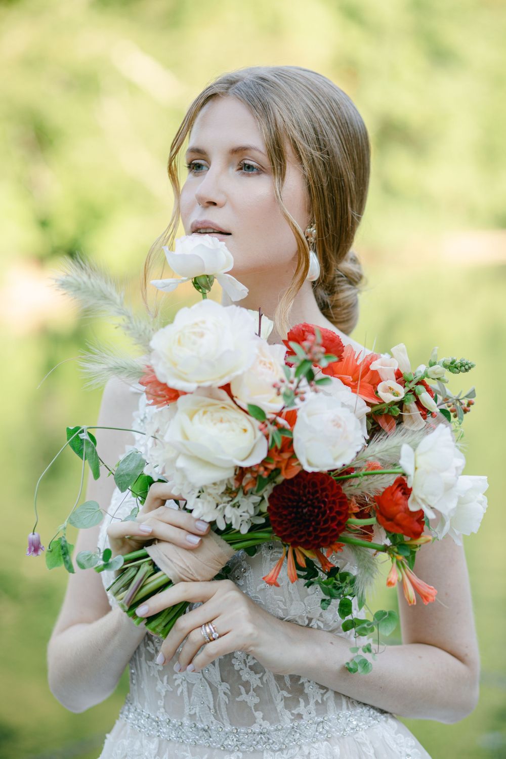 Elegant bridal portrait with white and red bouquet against soft natural background.