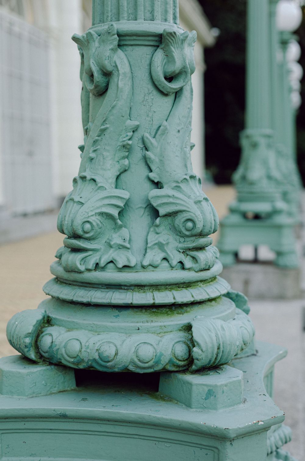 Ornate seafoam green architectural column detail with decorative scrollwork.
