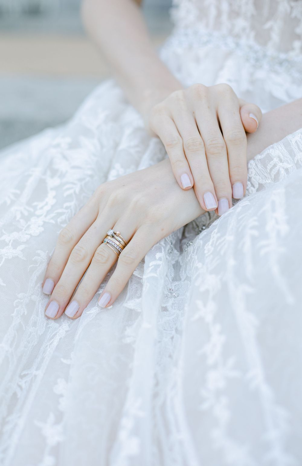 Delicate lace wedding dress detail with hands showing elegant ring placement.