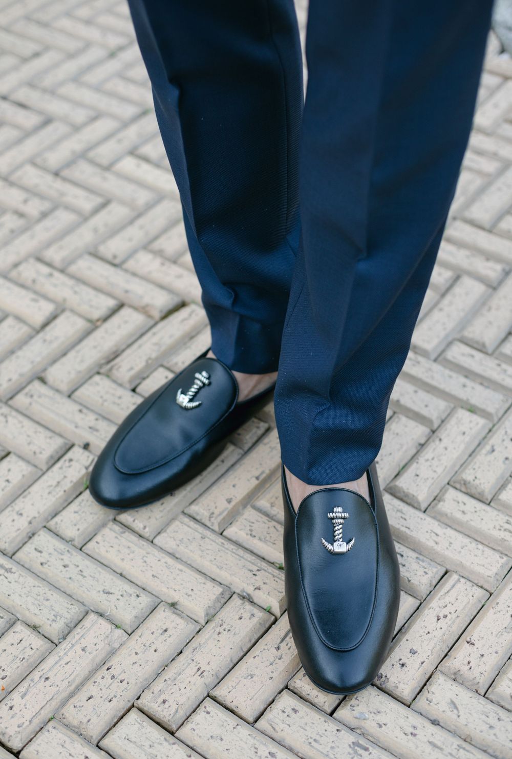Navy blue dress pants and loafers with anchor details on a brick patterned ground.