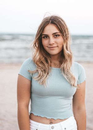 A beachside portrait featuring light blue crop top and casual summer style.