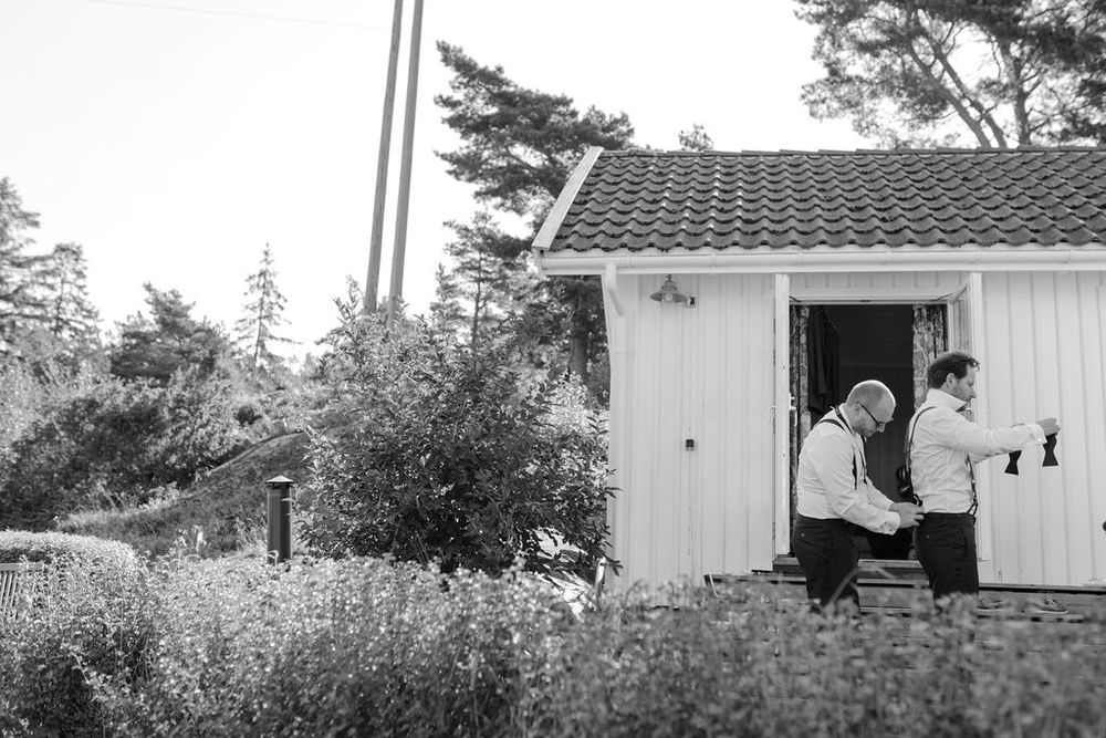 Black and white photo of cozy cottage with people sitting on porch steps.