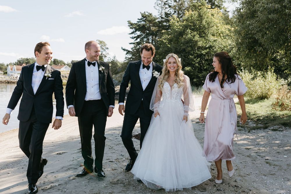 Wedding party walks together on path, featuring groomsmen and bridesmaids in formal attire.