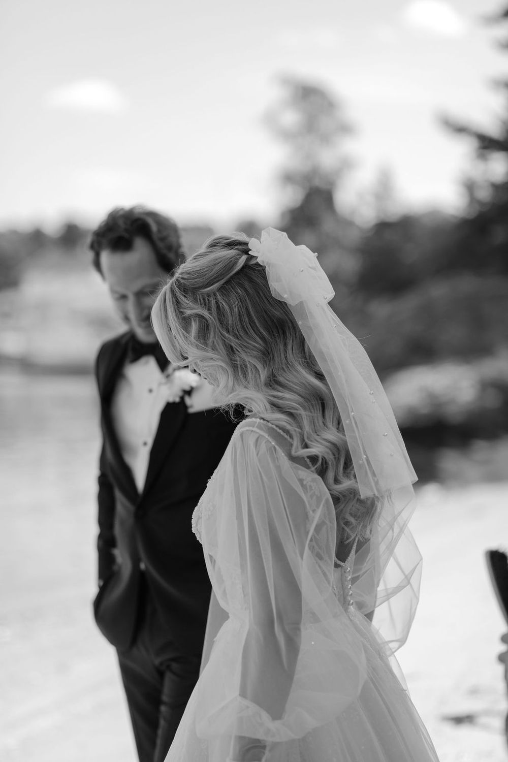 Black and white image of a bride in a flowing veil on her wedding day with romantic silhouette.