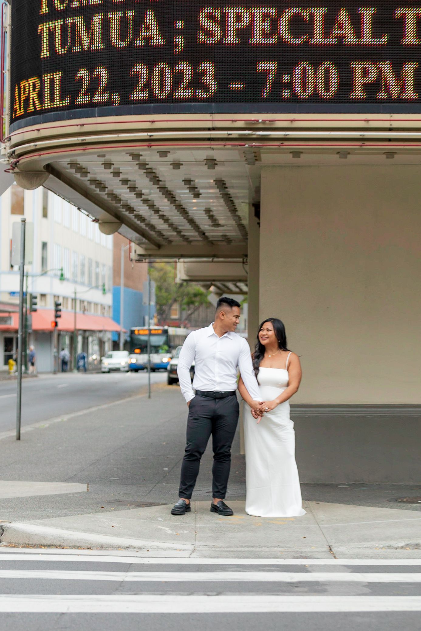 A couple poses under a vintage theater marquee displaying April 22, 2023.