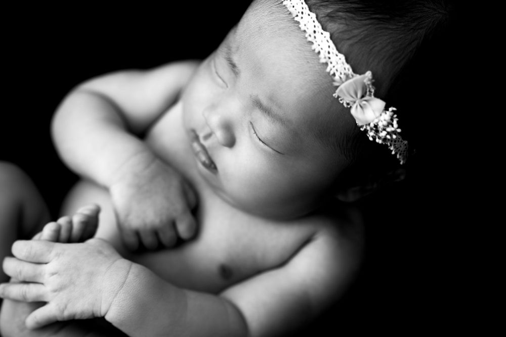 Black and white artistic newborn photography with soft lighting and shadows.