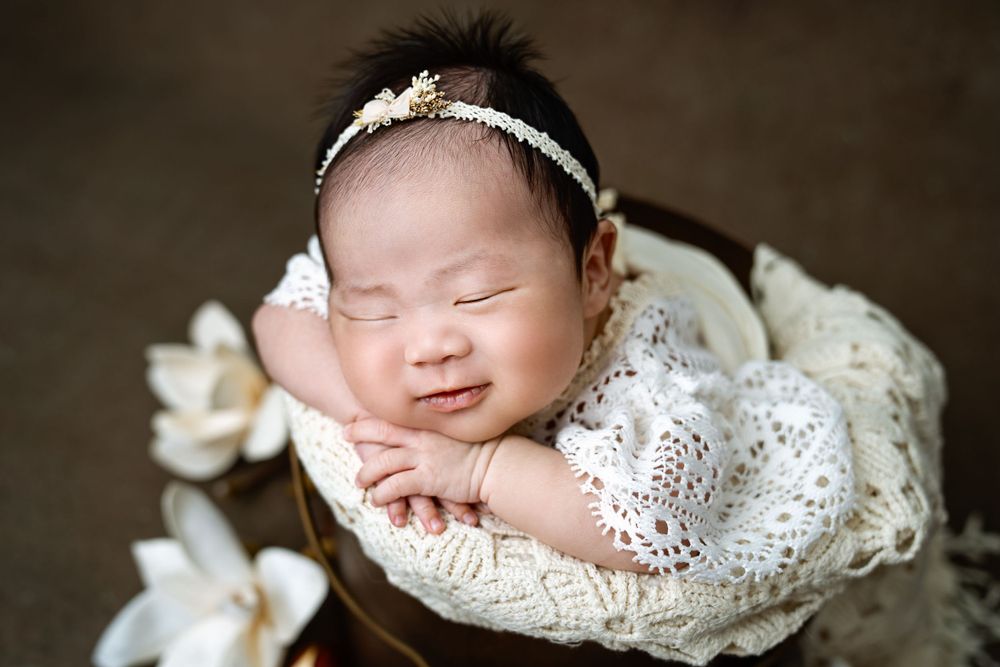 Vintage inspired newborn photography with lace details against dark background.