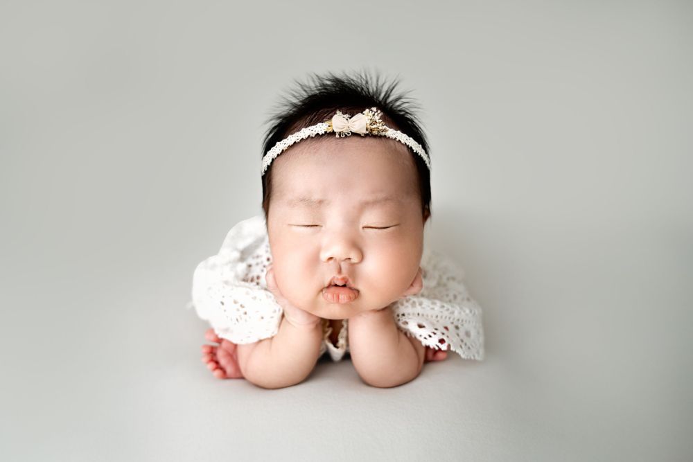 Minimalist newborn photography featuring white lace wrap and headband.