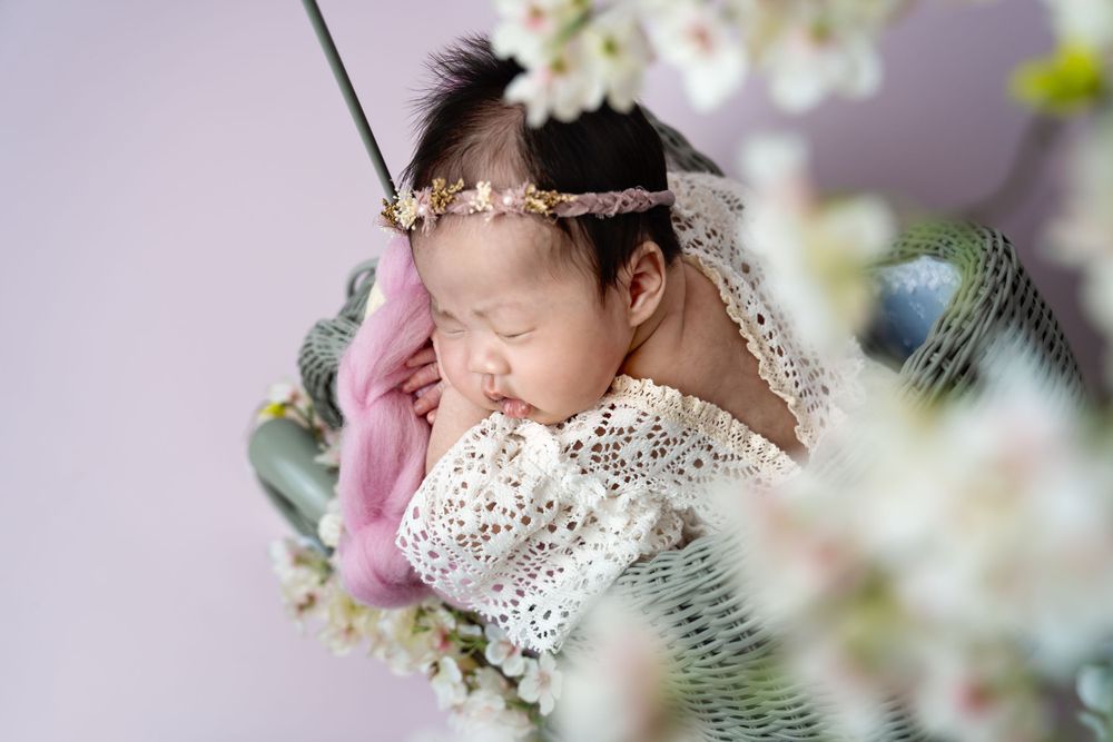Ethereal newborn portrait with spring blossoms and delicate lace details.