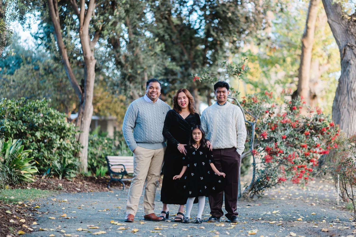 Group portrait of family standing on autumn path with fallen leaves.