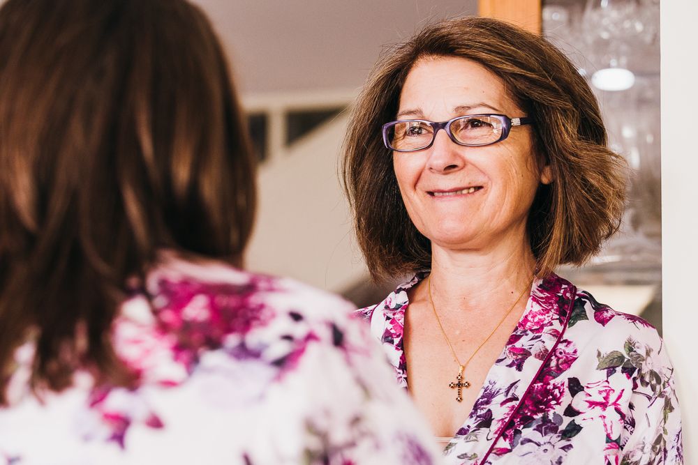 Candid portrait of someone wearing glasses and a floral robe smiling warmly.