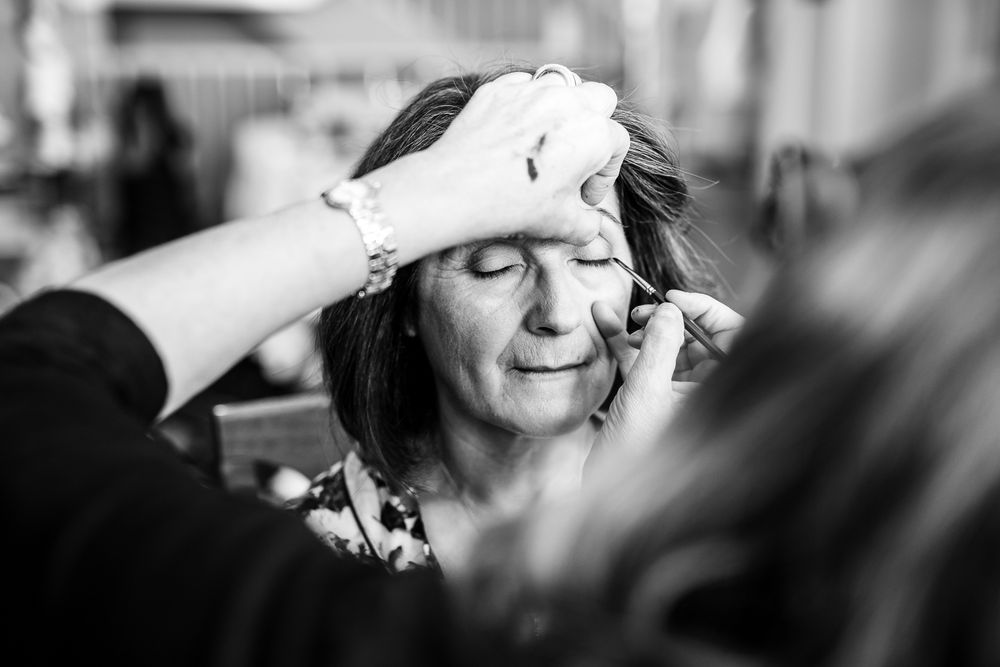 Black and white image showing makeup application during a preparation session.