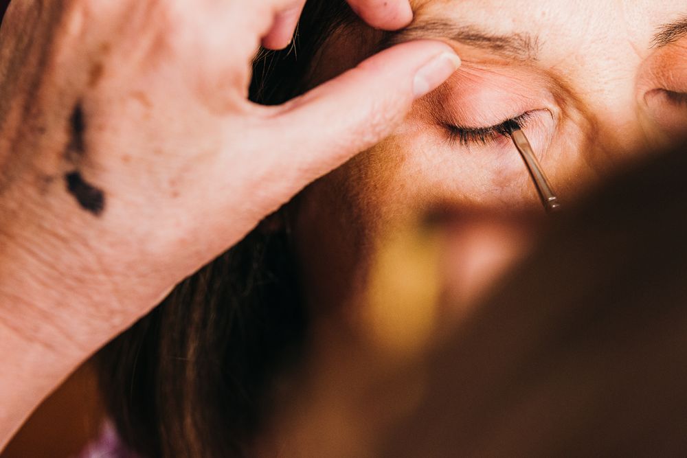 Close-up shot of someone applying makeup to an eye with delicate precision.