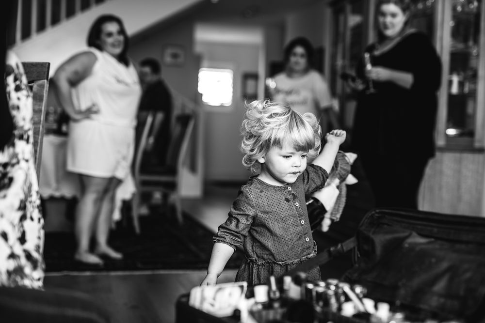 Black and white image of a young child in a dress during a special event.