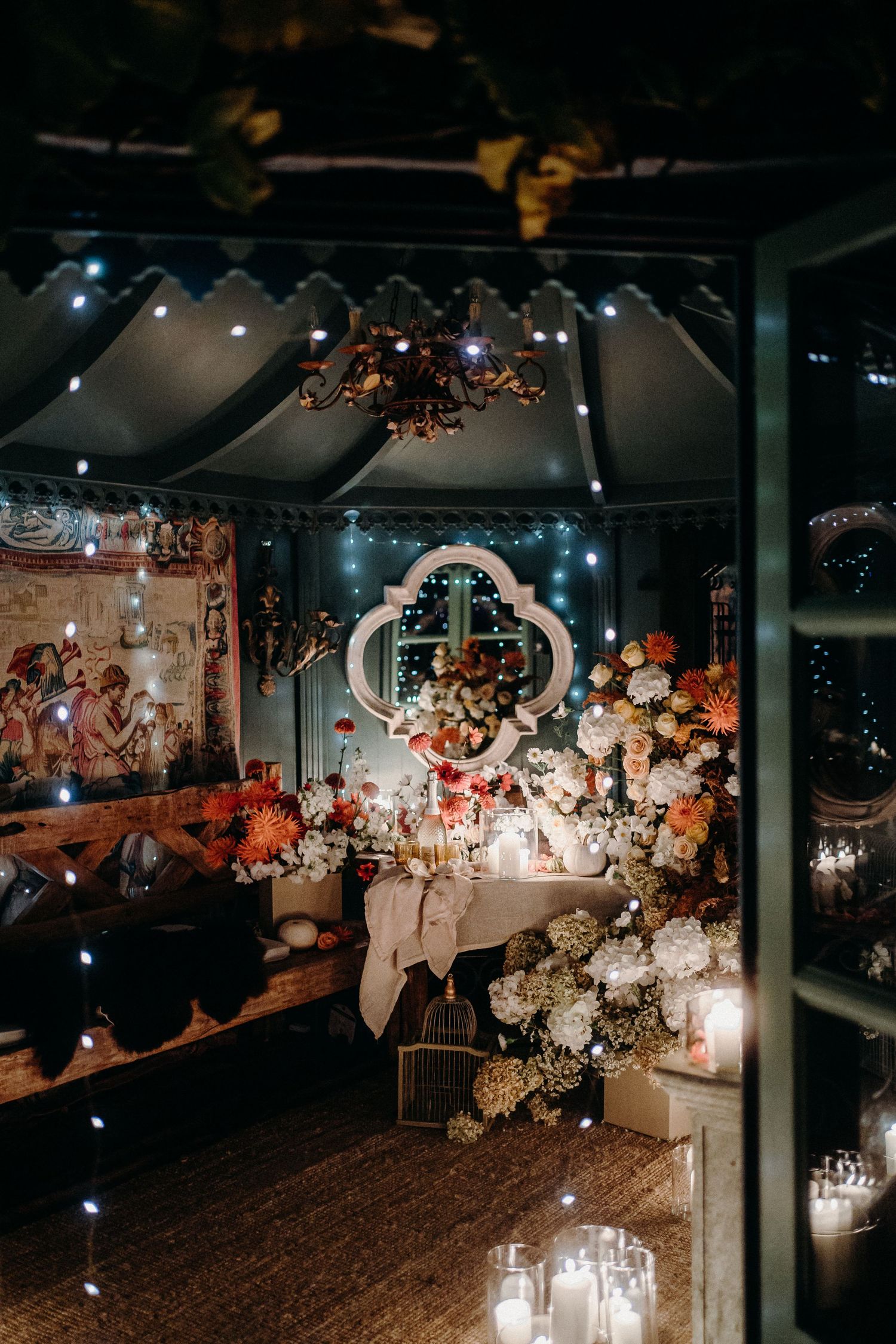 A romantic wedding venue decorated with candles, flowers and ornate details in moody lighting.