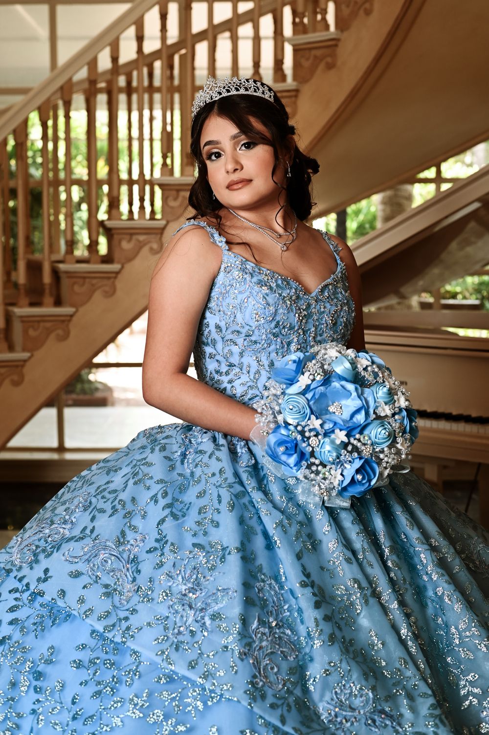 Elegant ballgown in light blue with intricate lace detailing and a matching bouquet.
