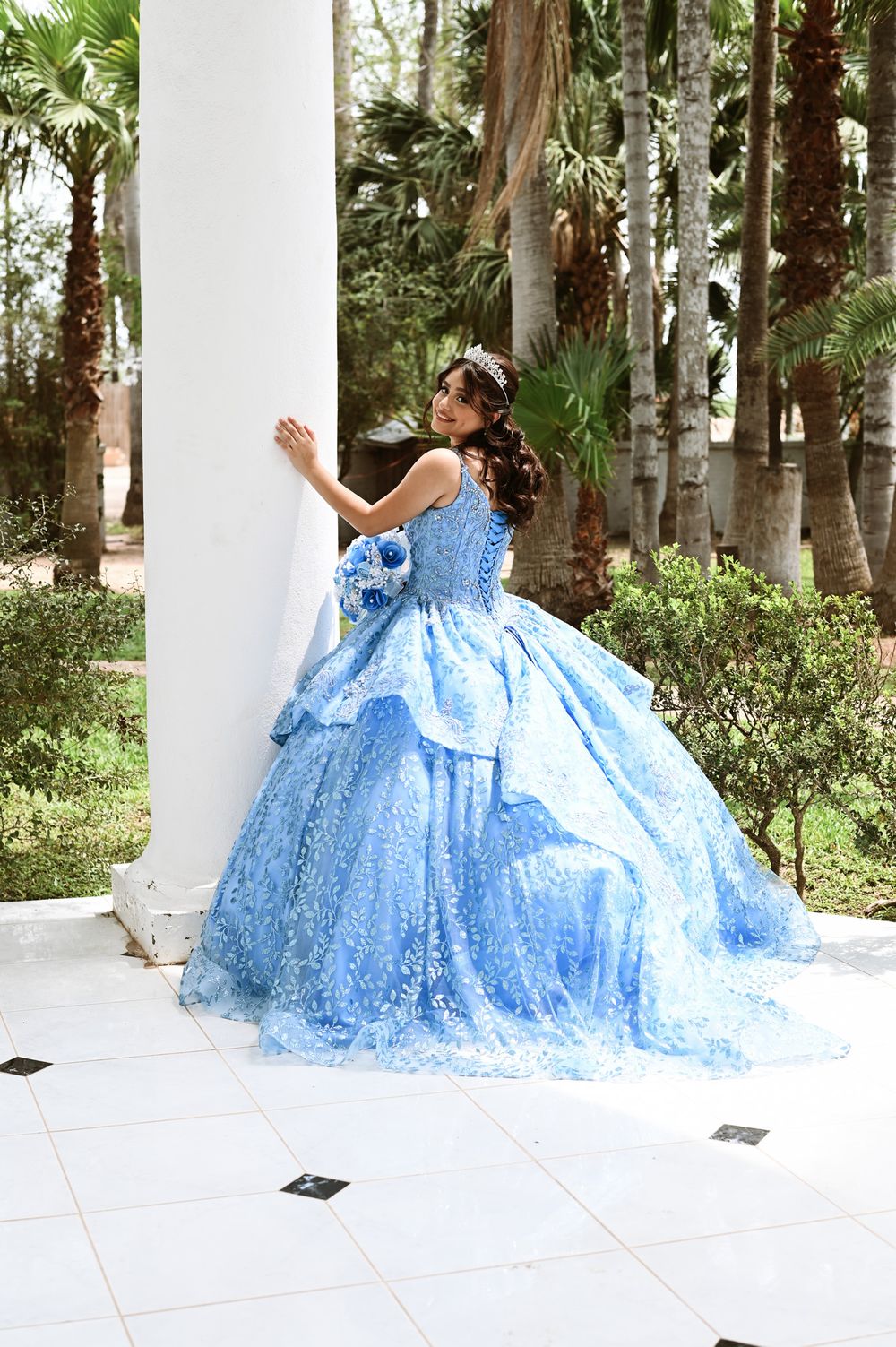 Cinderella-inspired blue ball gown photographed against white colonial pillars outdoors.