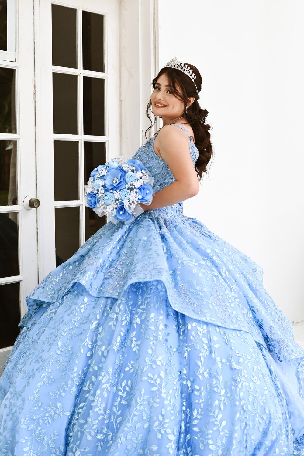 Elegant blue ball gown with tiered skirt and lace details photographed by French doors.