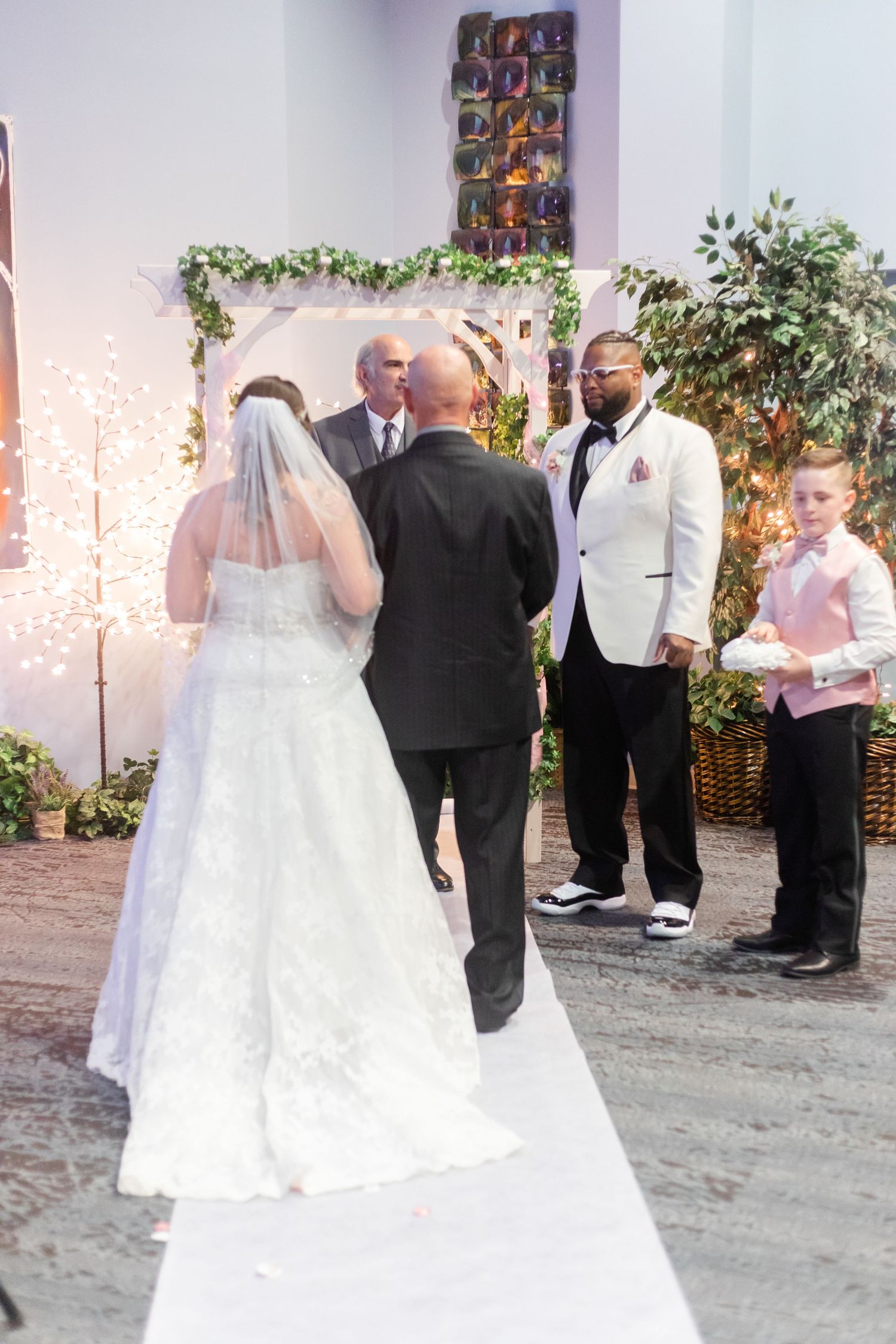 Wedding ceremony in progress with formal attire and decorative backdrop.