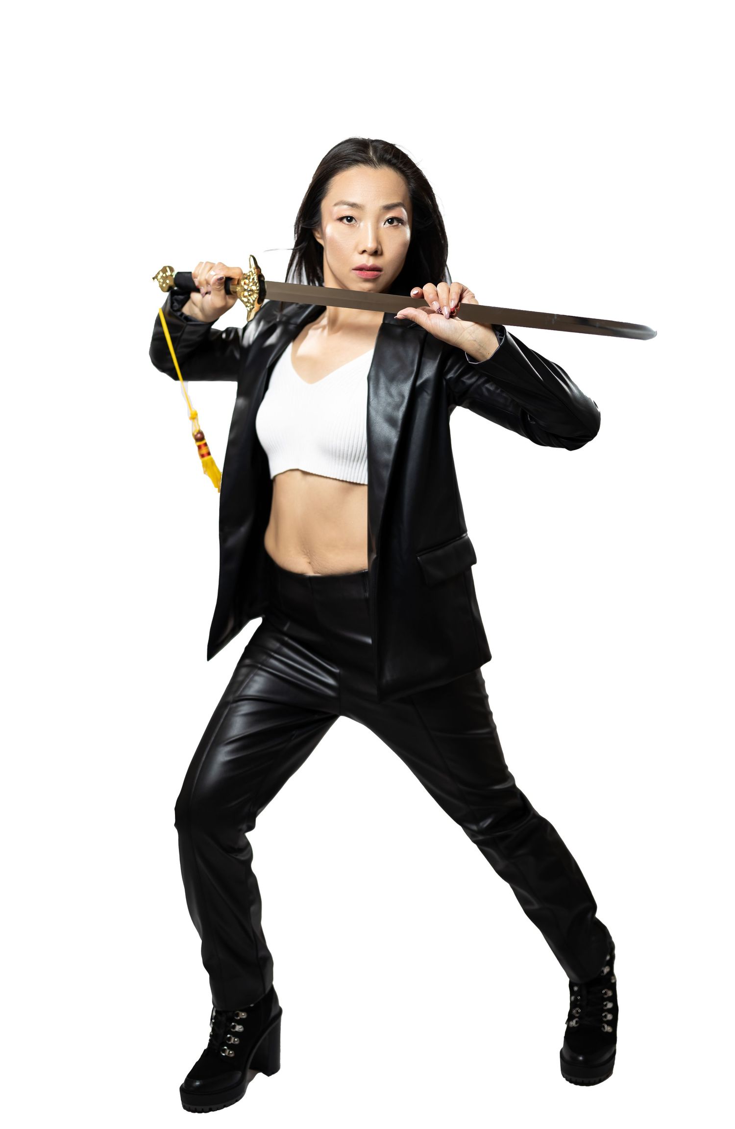 Action shot of martial artist posing with sword in black outfit.