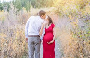 A tender moment captured outdoors with a couple in formal wear against a natural autumn backdrop.