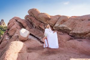 White dress and decor items displayed on red rock formations against blue sky.