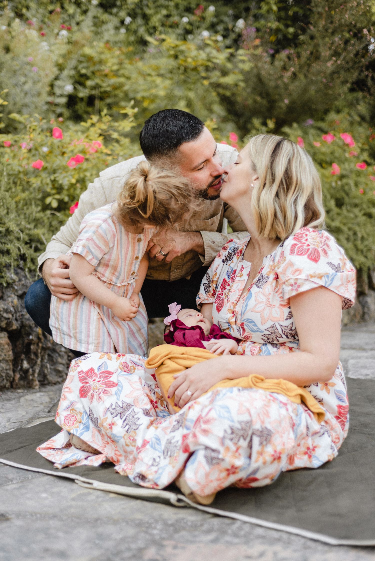 Intimate family moment shared outdoors in a blooming garden.