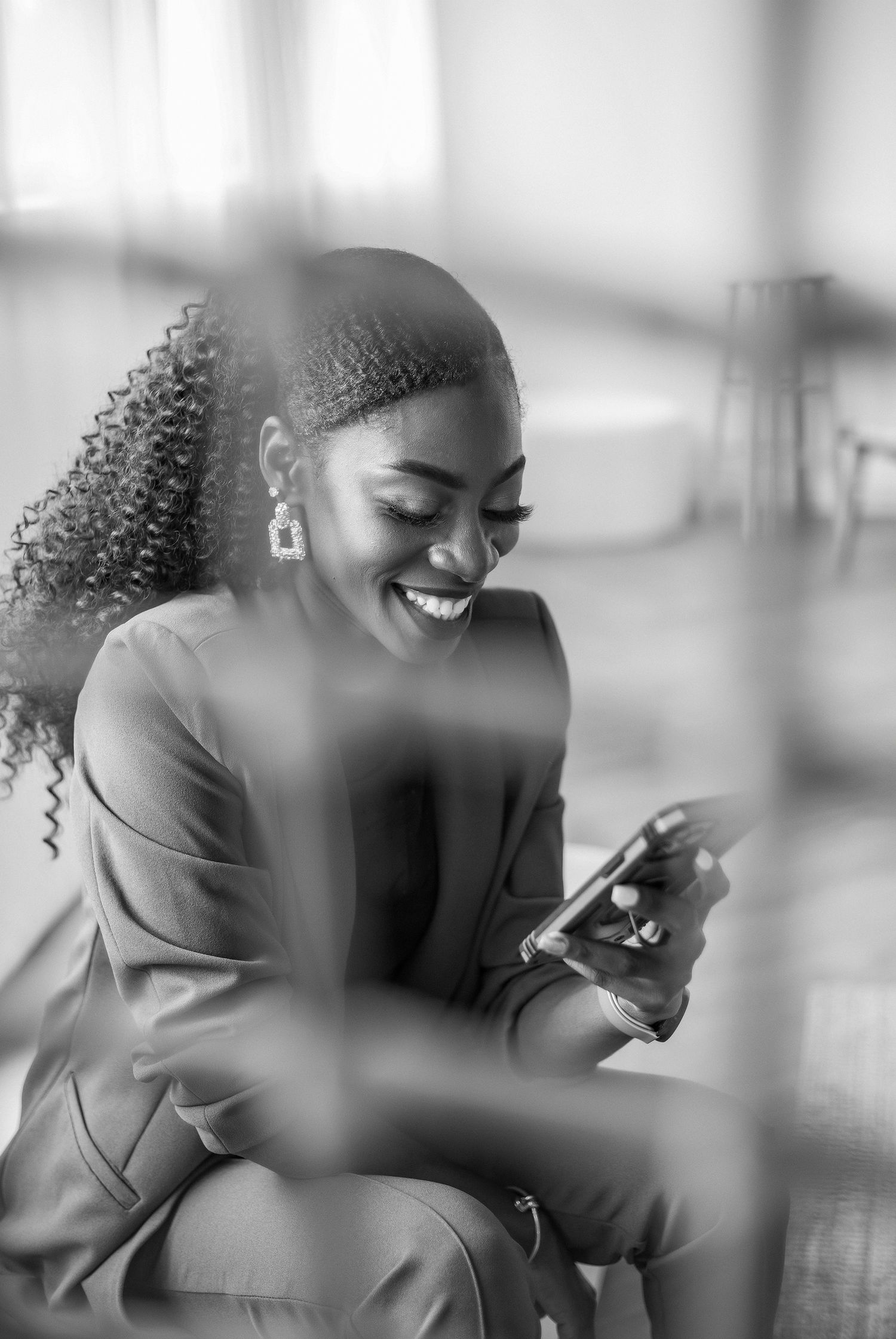 Joyful black lady smiling at phone, radiating happiness and positivity in a candid and beautiful moment.