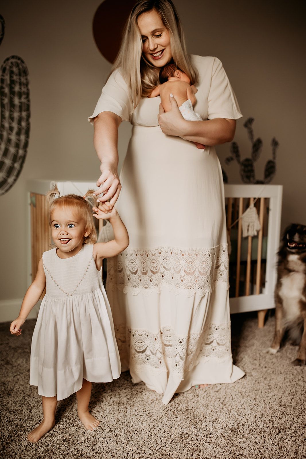 A mother dances with her daughter while holding her new baby boy.