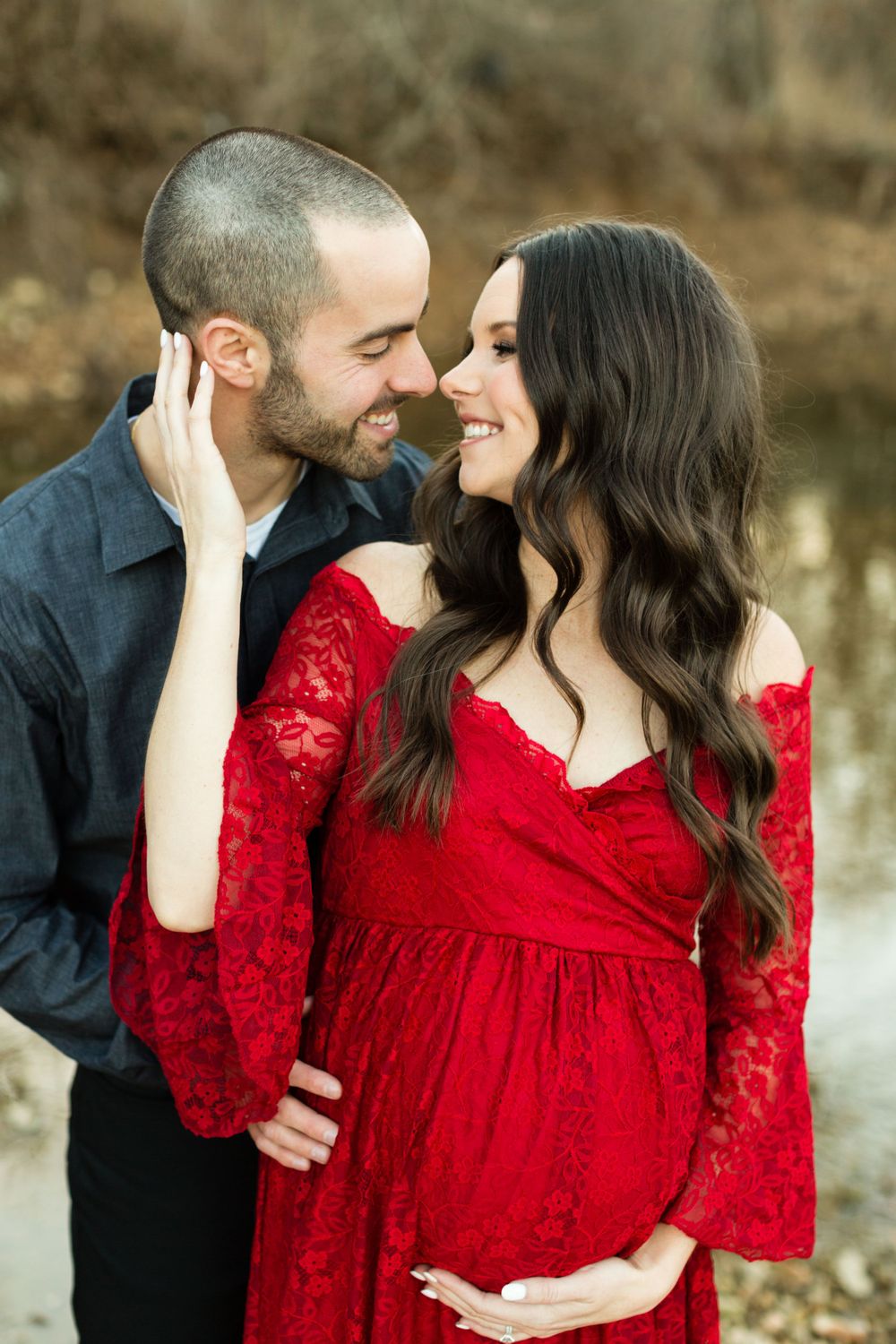 Intimate maternity portrait of couple in formal wear against natural backdrop.