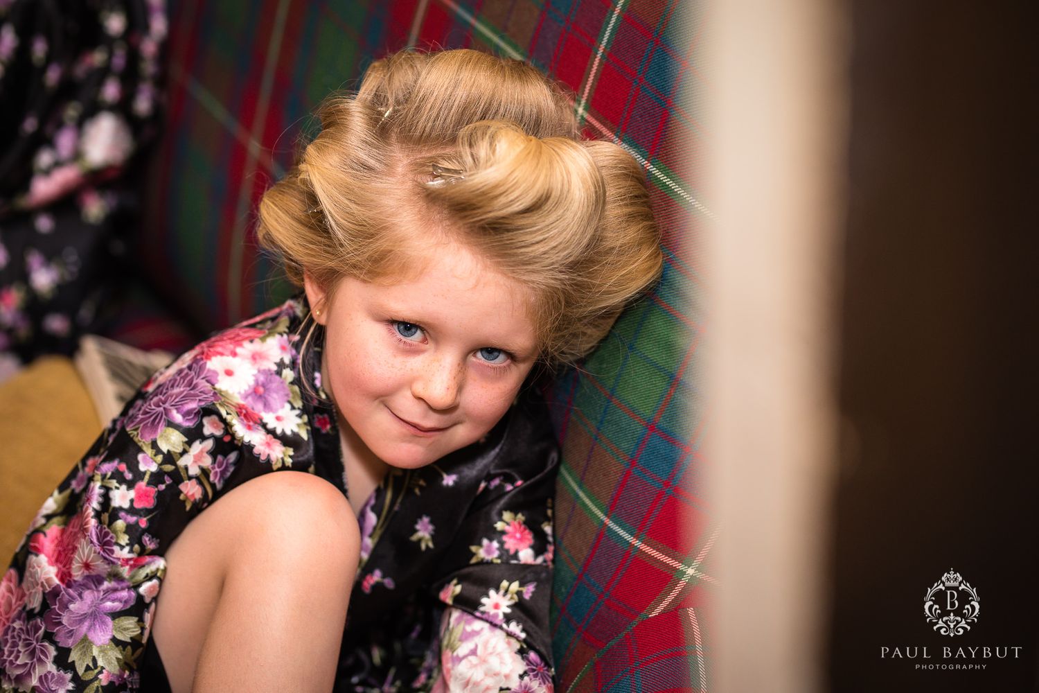 Portrait showing floral pattern dress against plaid background in warm lighting.