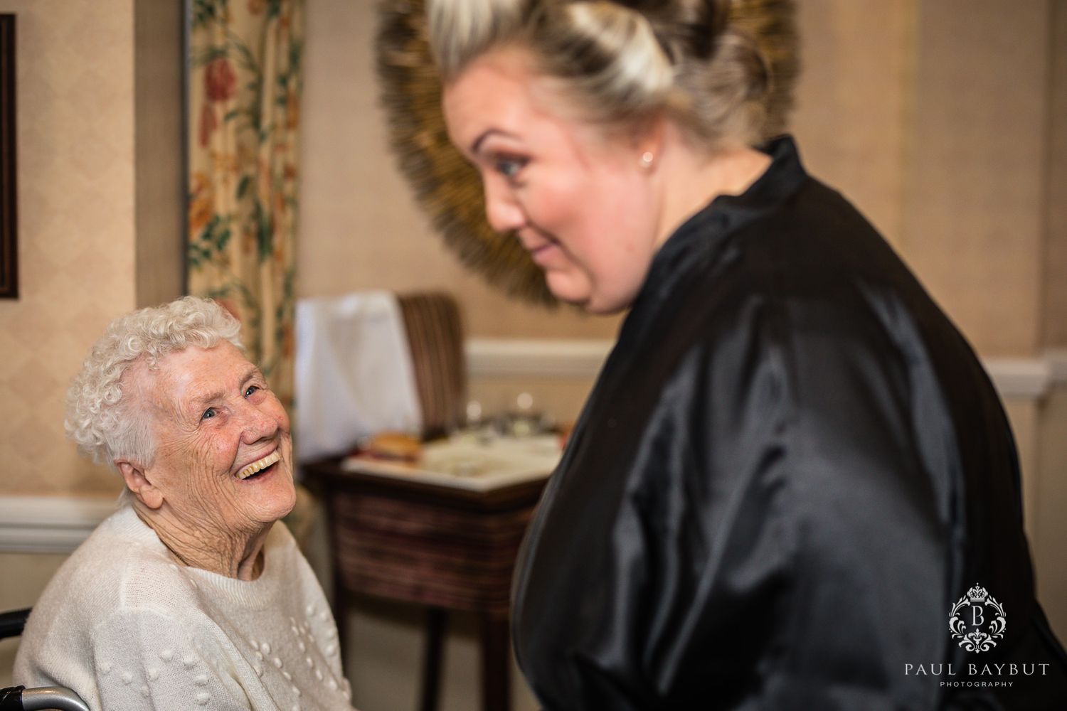 Two people share a joyful moment as they laugh together in a warmly lit room.