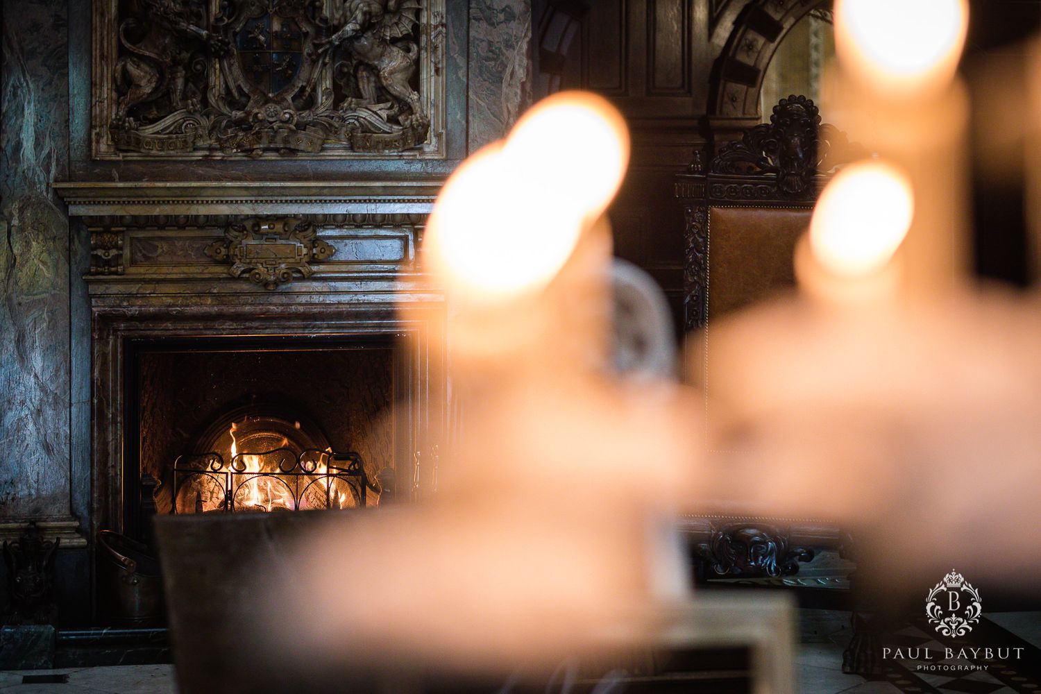 Candlelit scene with ornate fireplace and blurred candles in foreground.