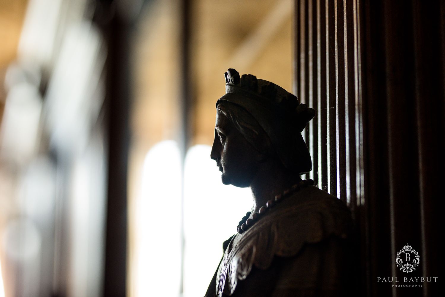 Silhouette of a decorative statue against window light in a historic interior setting.