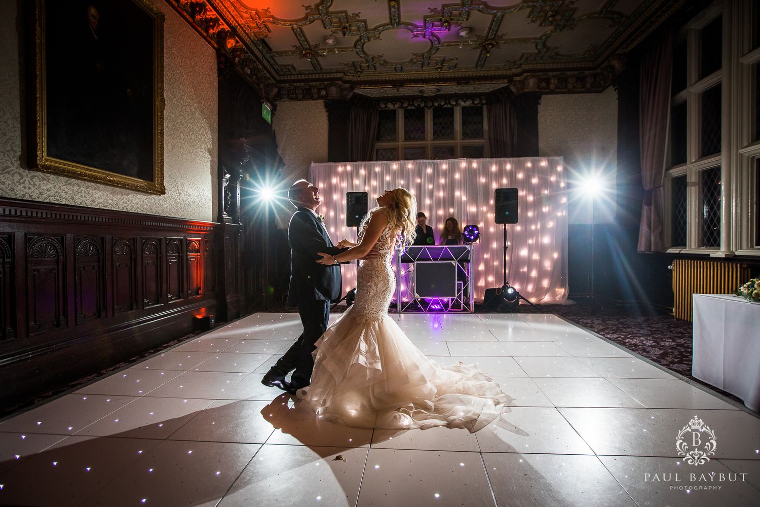 Dramatic first dance moment on an illuminated dance floor with twinkling lights and elegant decor.