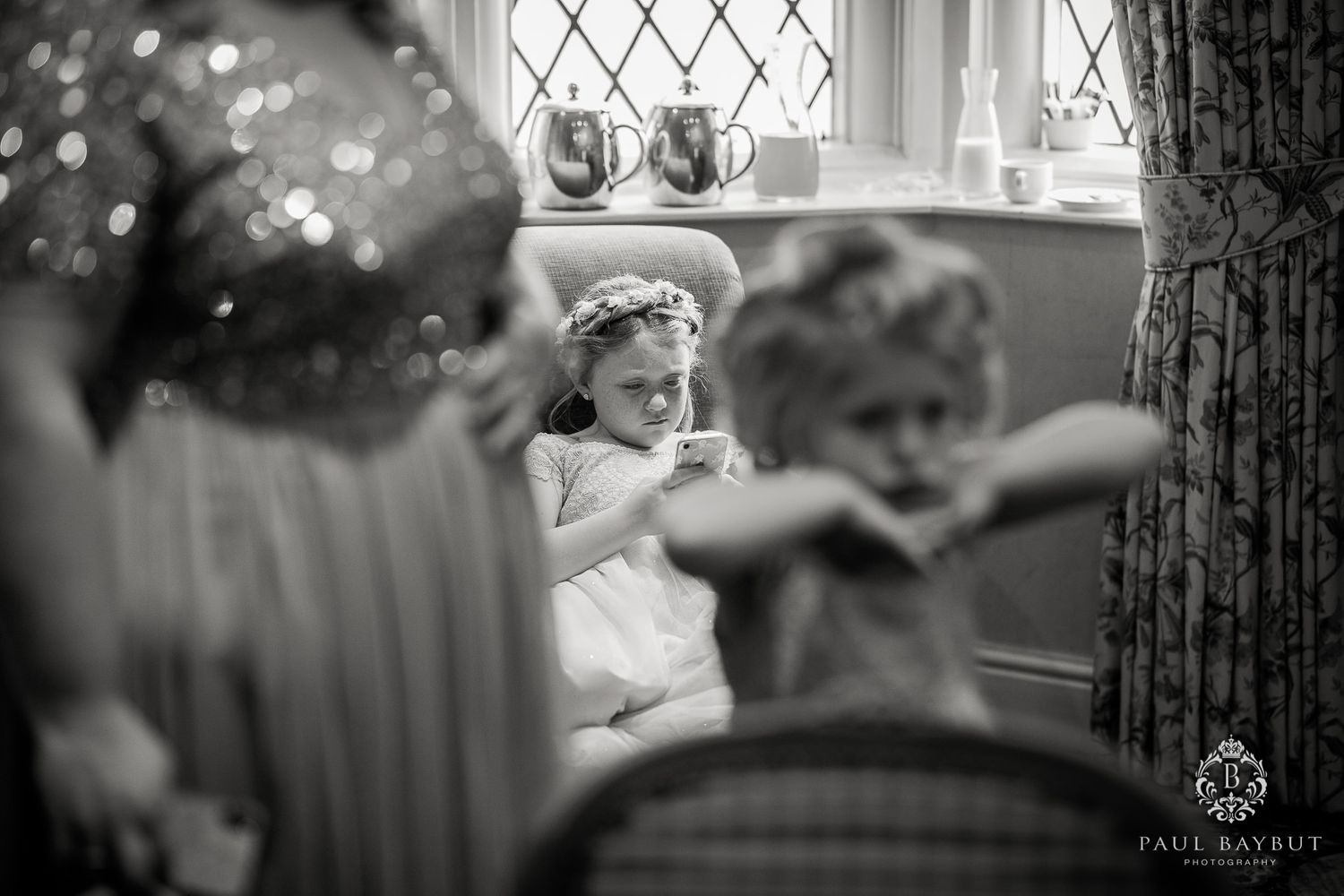 Black and white candid photo of wedding preparations through decorative window.