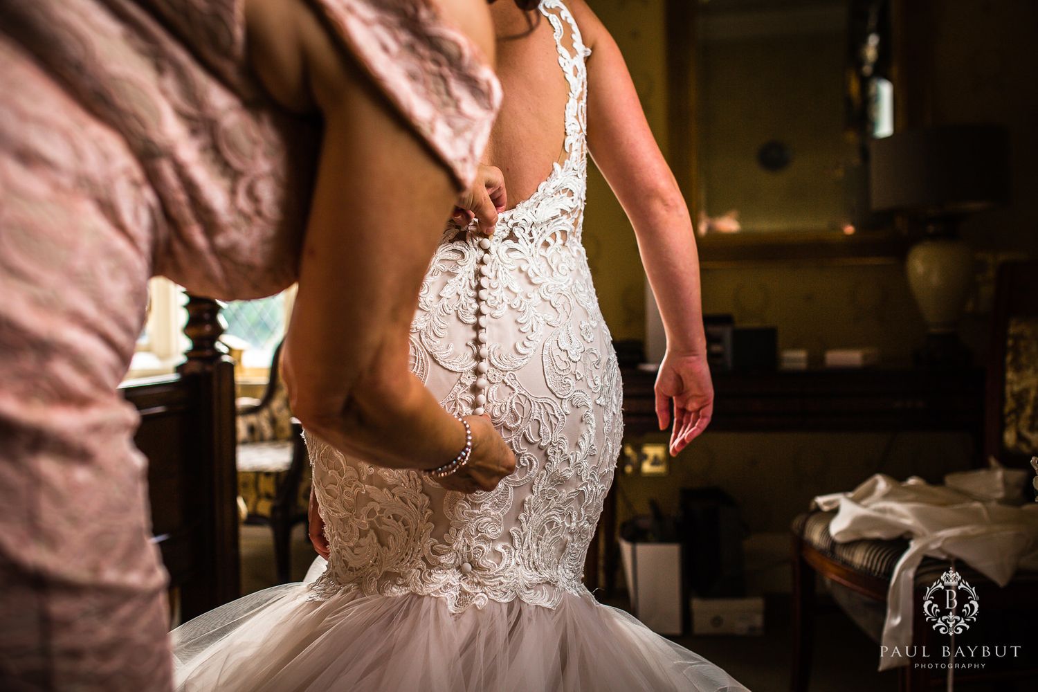 Back detail of a fitted lace wedding gown with button closures.