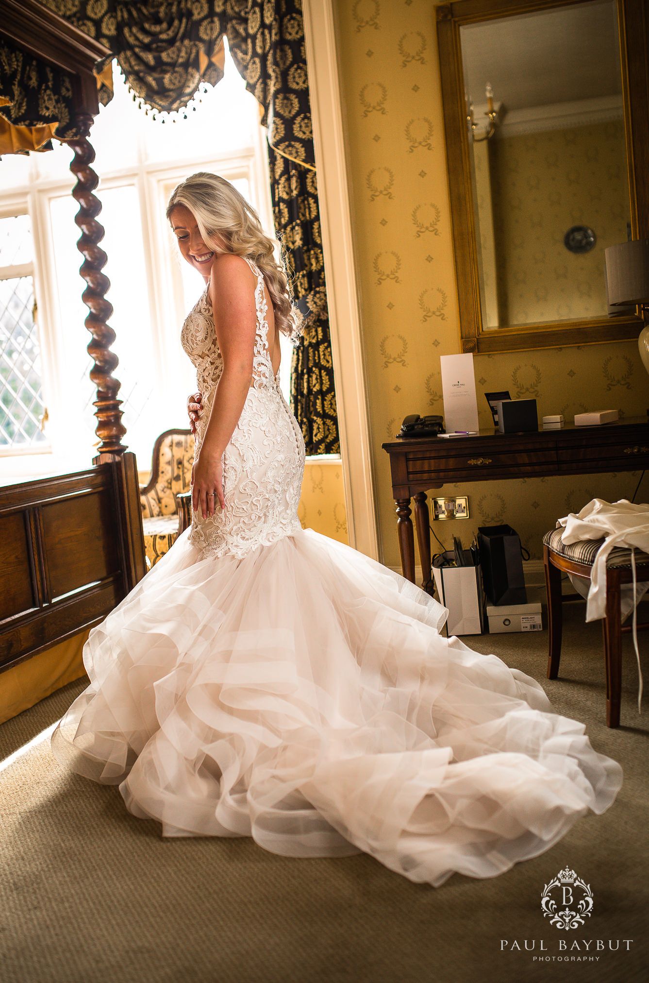 Dramatic mermaid wedding gown with flowing tulle skirt in an elegant room setting.