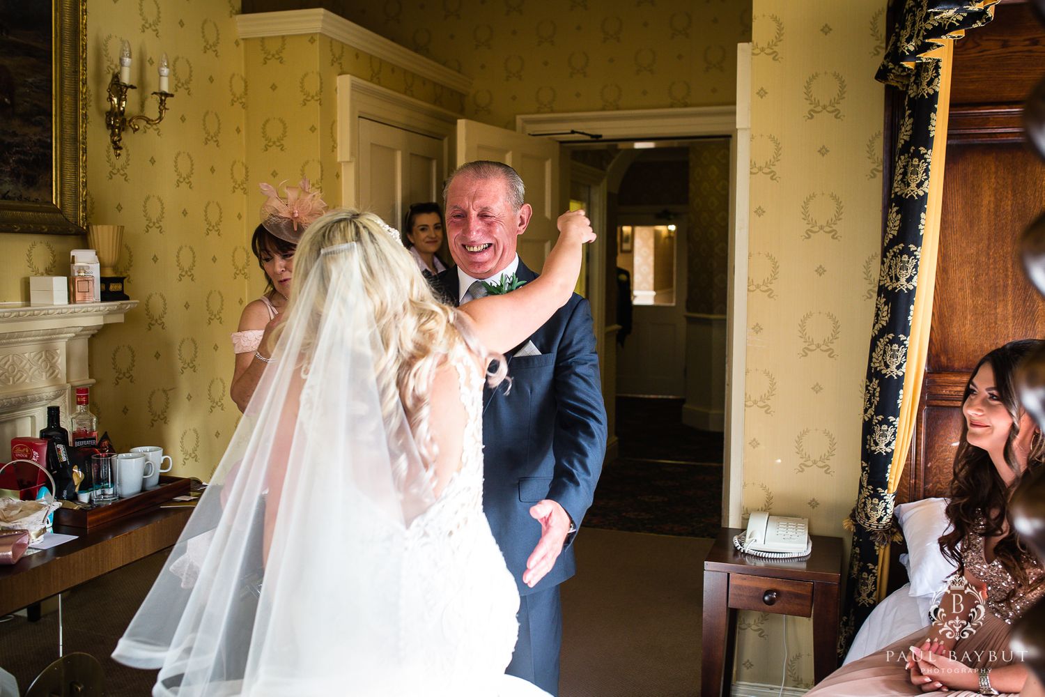Emotional first look moment captured during wedding preparations in a vintage-styled room.