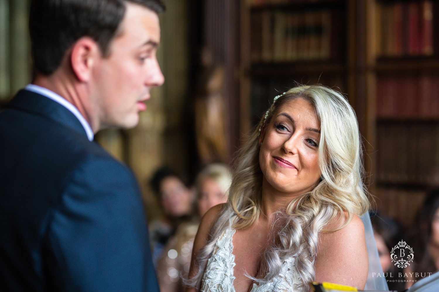 A couple exchanges loving glances during their wedding ceremony in a historic library.